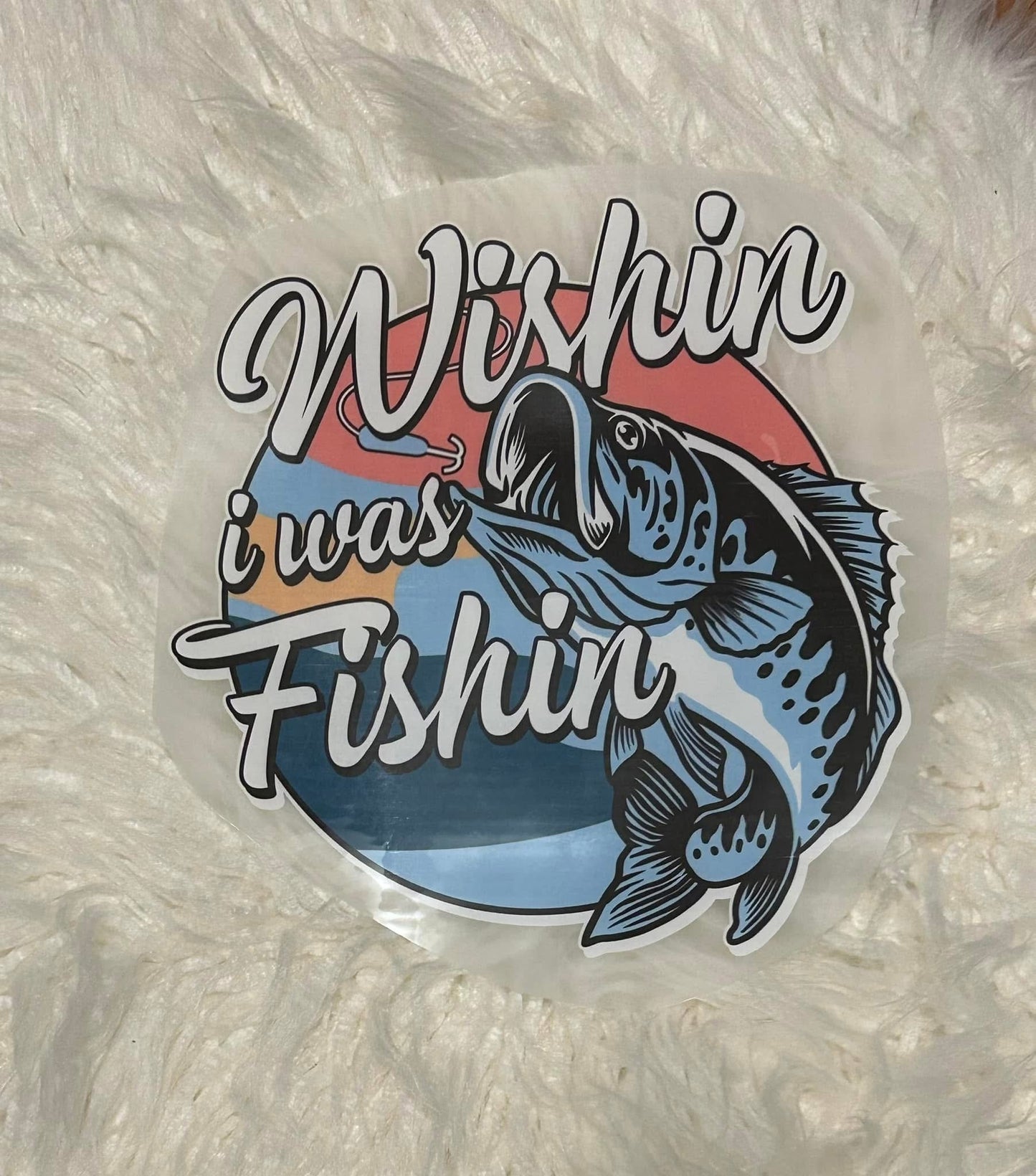 Sticker with a fish and text 'Wishin i was Fishin' on a textured white background