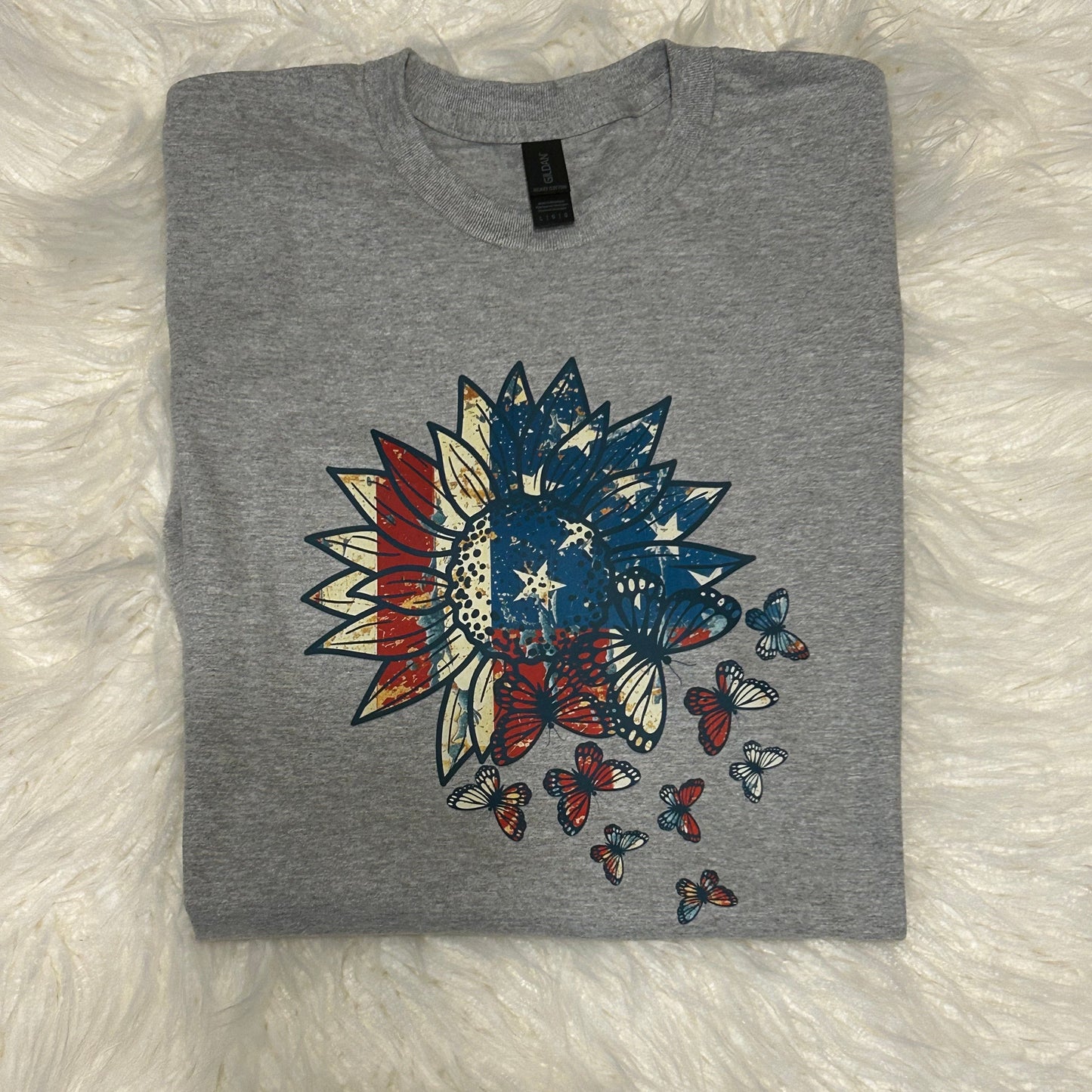 Gray t-shirt with a colorful graphic design on a white fluffy surface