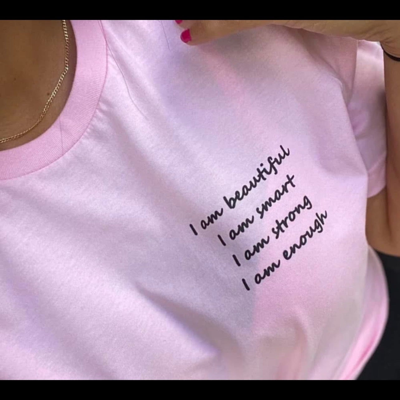 Pink top with motivational text on a plain background