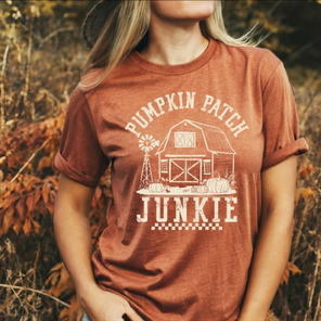 Person wearing a red t-shirt with 'Pumpkin Patch Junkie' design in a natural setting