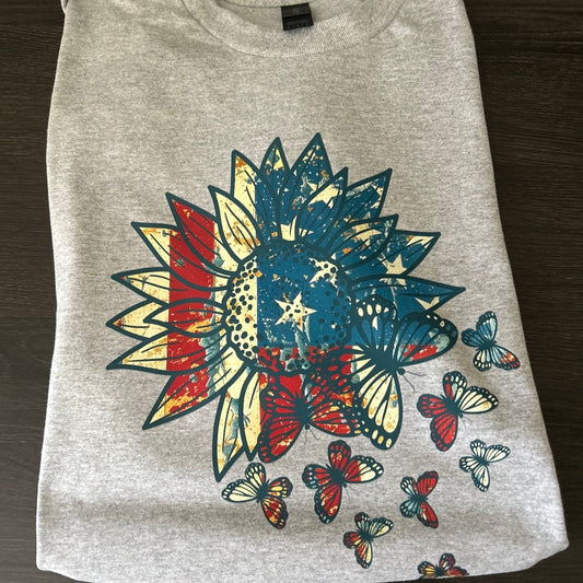Gray t-shirt with colorful butterfly and flower design on a wooden surface
