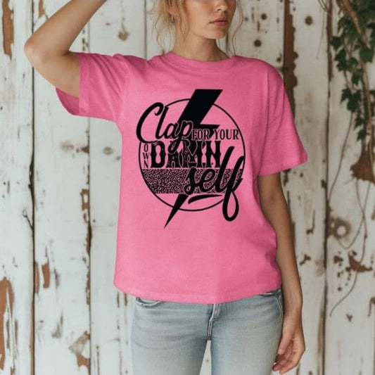 Person wearing a pink t-shirt with black graphic design against a wooden background