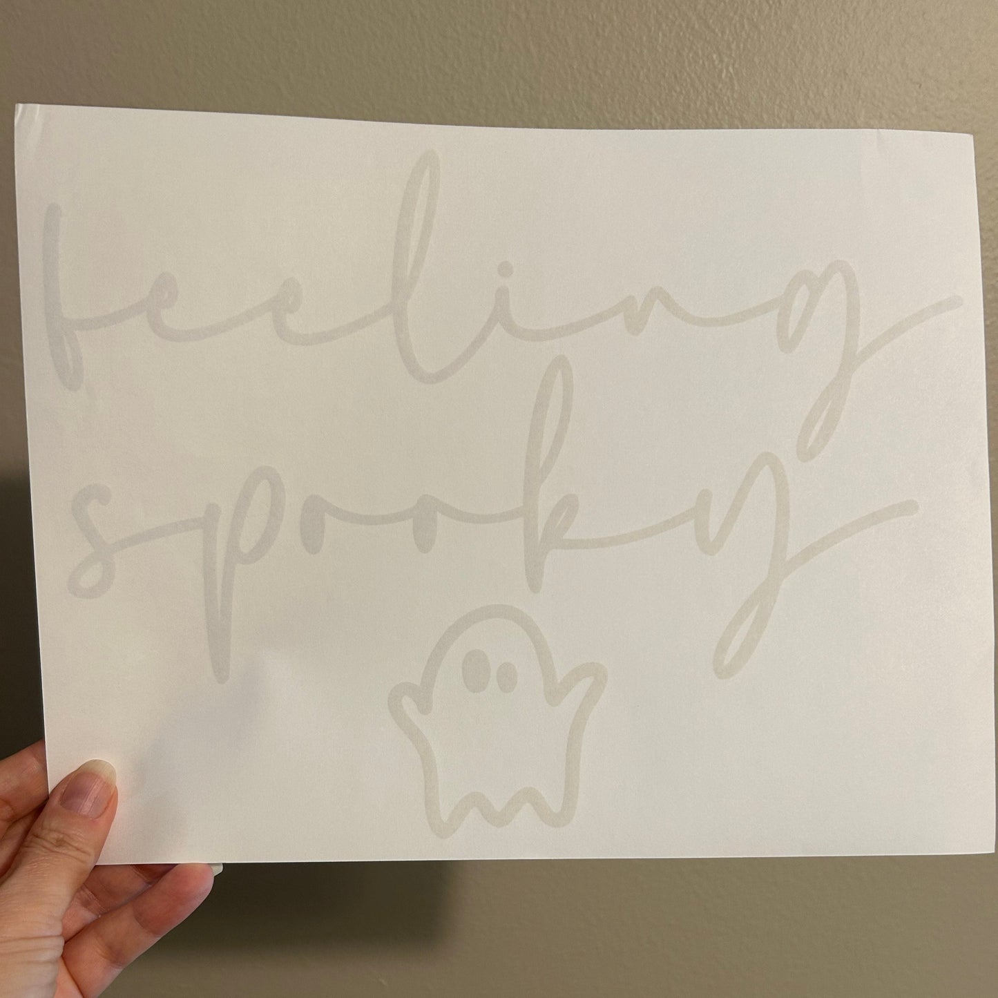 Hand holding a sheet of paper with printed outlines of cartoon characters against a plain background