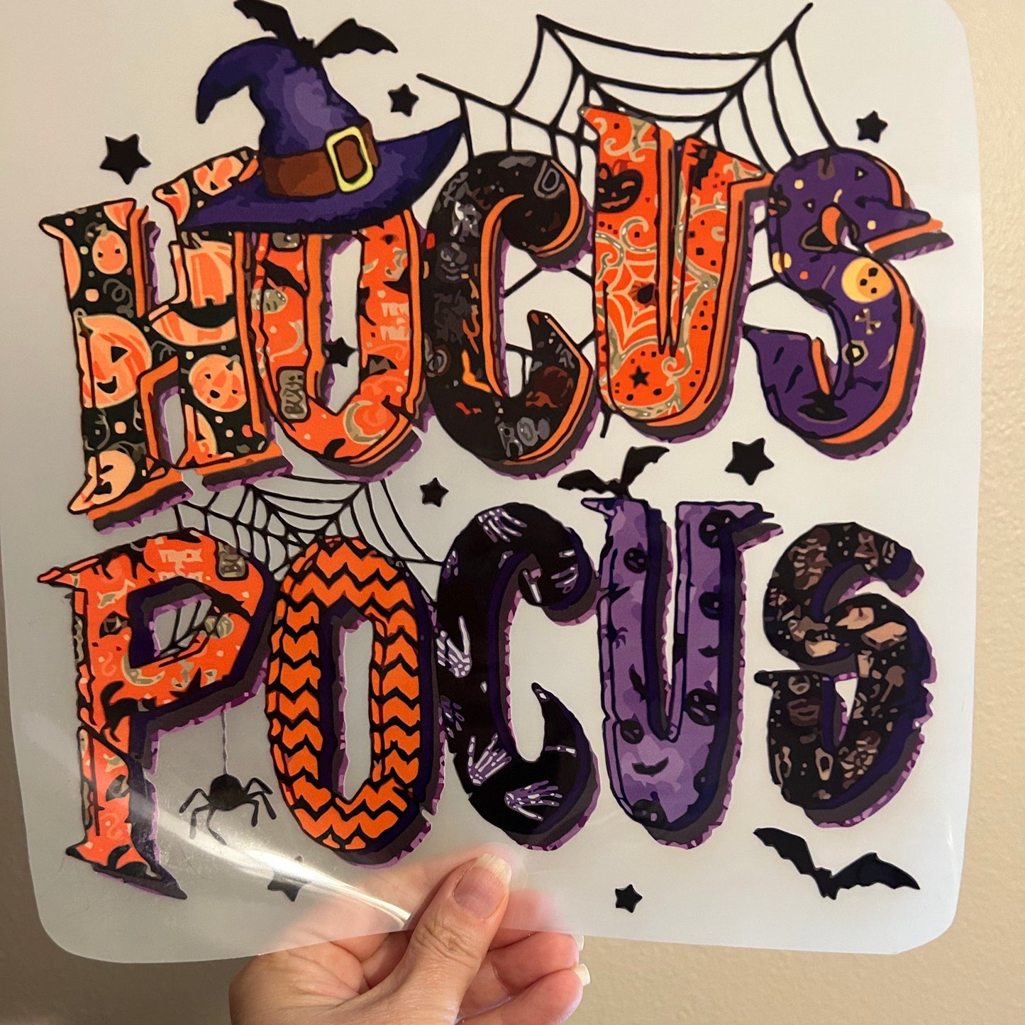 Sheet of Halloween-themed temporary tattoos held by a hand against a beige background