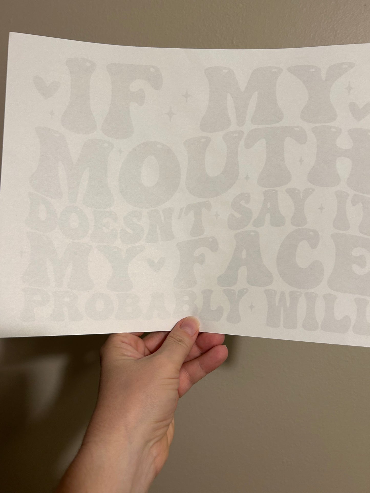 Hand holding a sheet of paper with text against a plain background