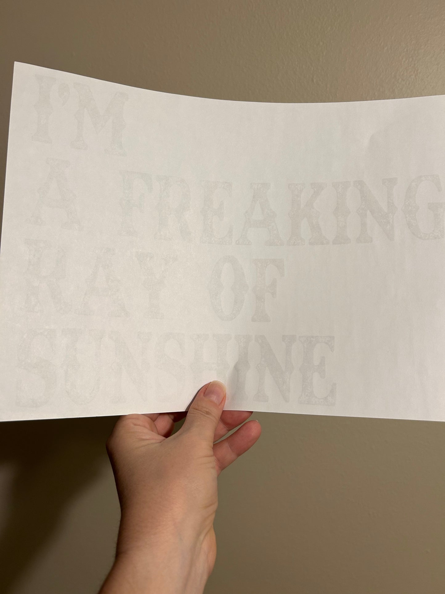 Hand holding a sheet of paper with embossed text against a plain background