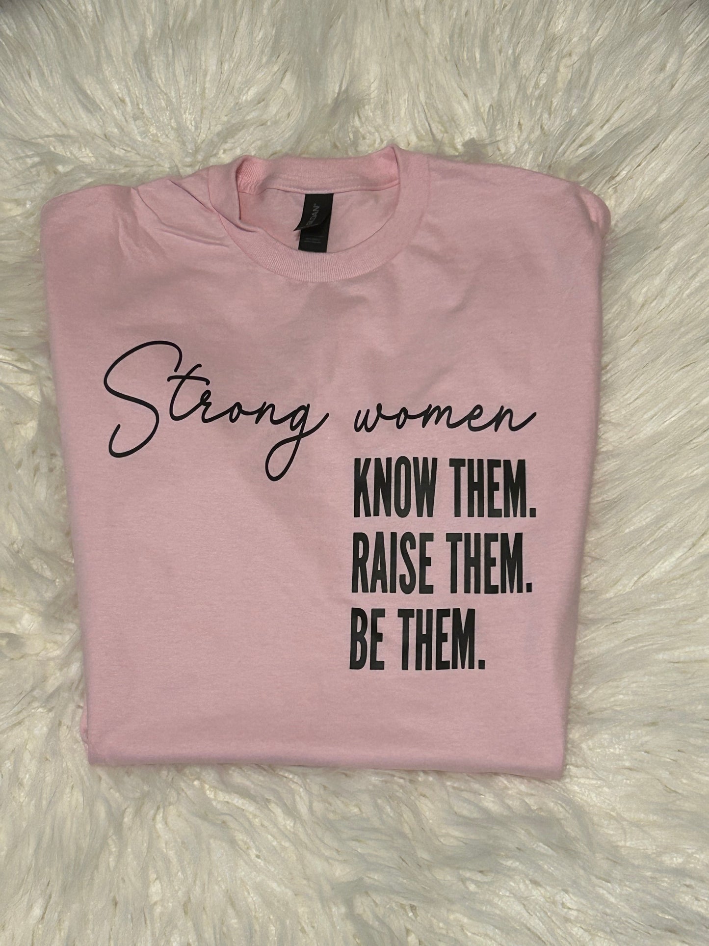Pink t-shirt with motivational text on a fluffy white surface
