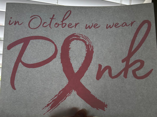 Gray card with pink ribbon and text 'in October we wear Pink' on a plain background