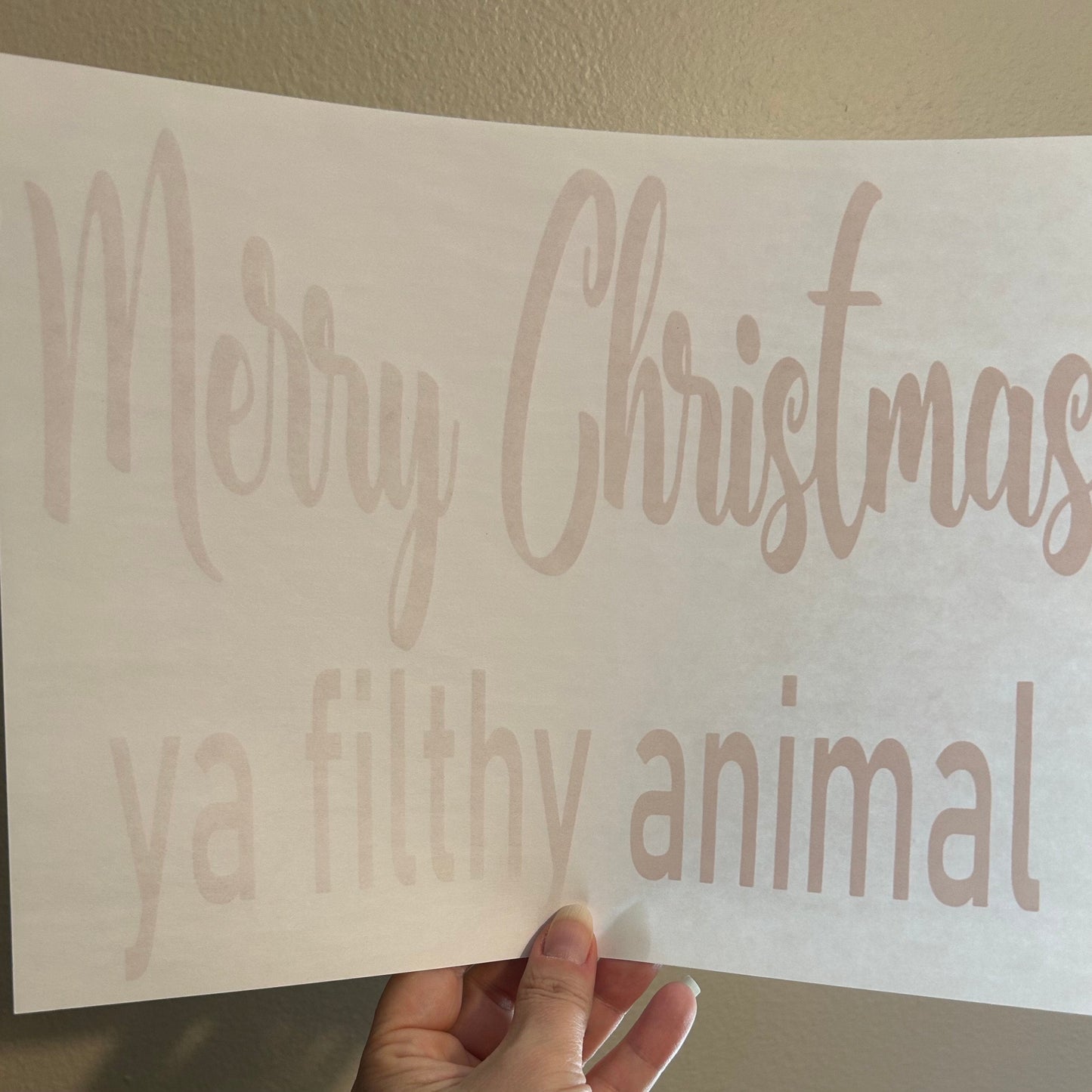 Card with 'Merry Christmas ya filthy animal' text held against a plain background