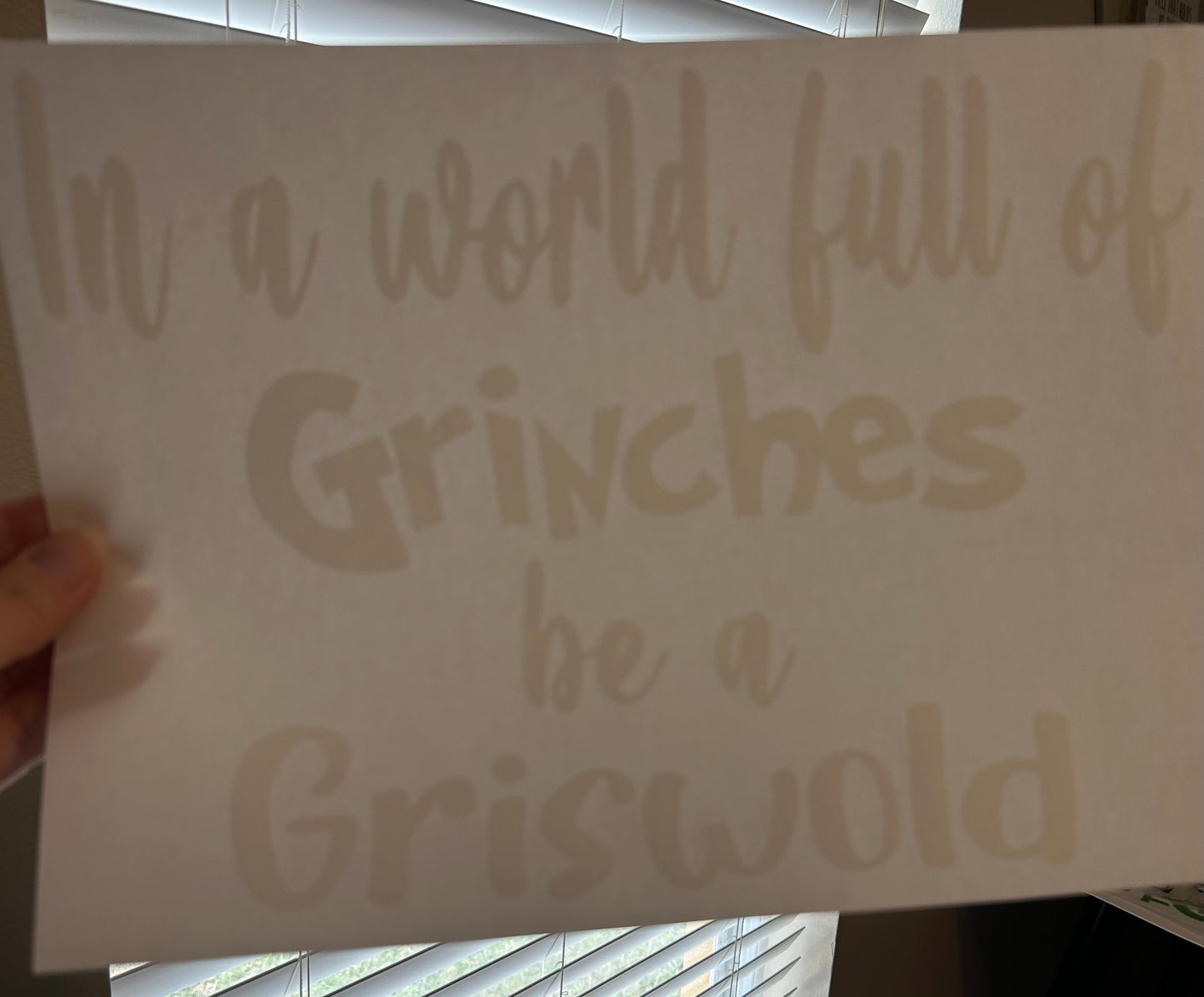 Decal with text 'In a world full of Grinches be a Griswold' held by a hand.