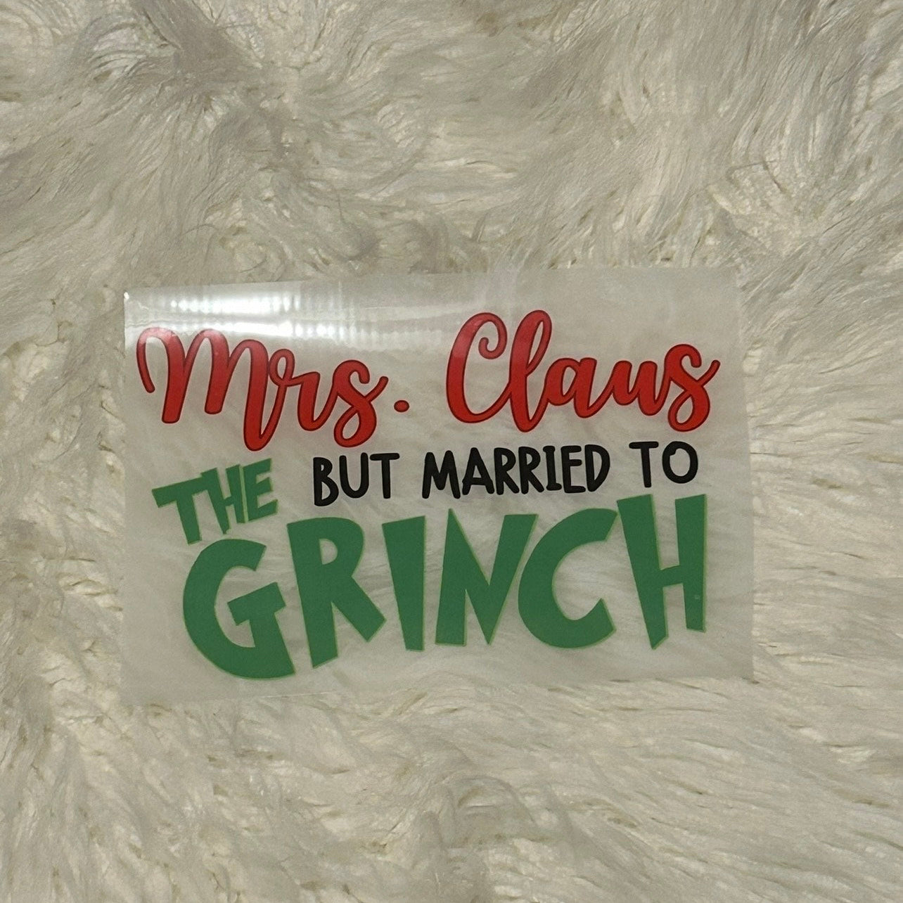 Sticker with text 'Mrs. Claus but married to Grinch' on a textured white background