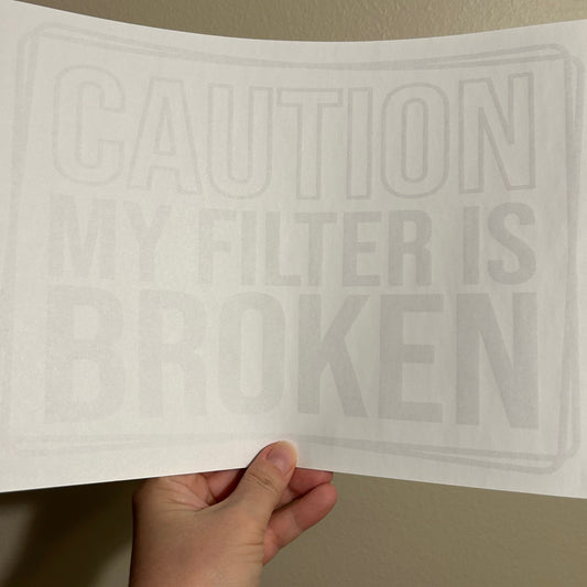 Hand holding a white filter with embossed text against a beige wall.