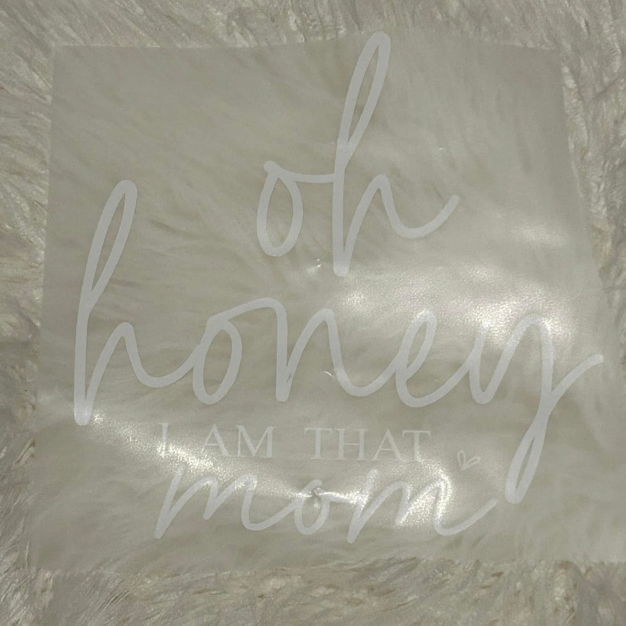 Decorative pillow with 'oh honey I am that mom' text on a textured surface