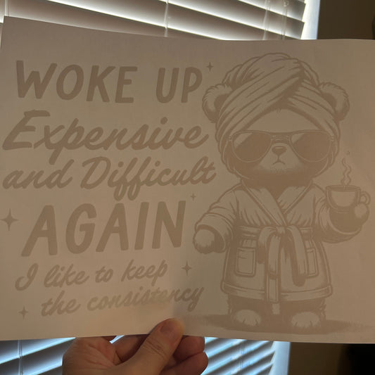Hand holding a printed sheet with a bear graphic and text against a window blind background